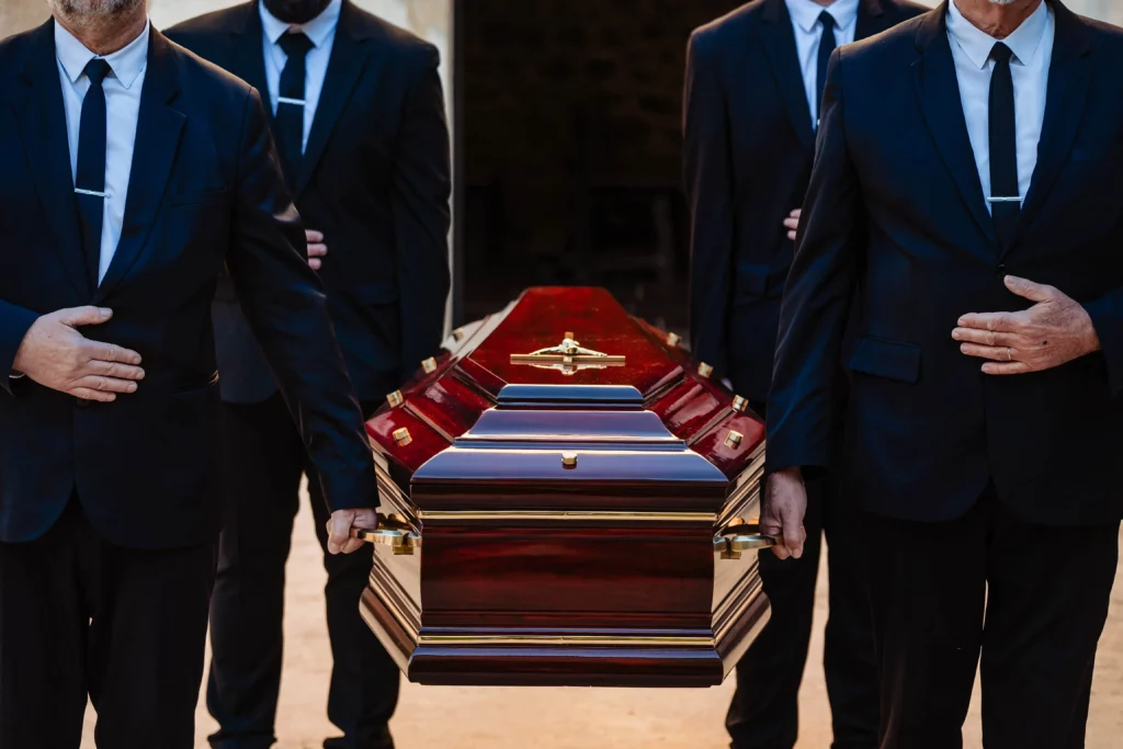 Porteurs funéraires en costume sombre portant un cercueil en bois verni.